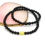 Juodos spalvos gintaro karoliai su išskirtine detale centre